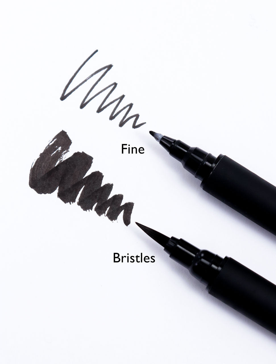 Close-up of a Sakura fine brush pen showing its pressure-responsive felt tip and jet-black pigment ink strokes.