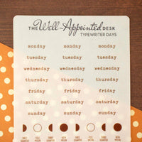 Weekly planner with days of the week and moon phases on a wooden surface.