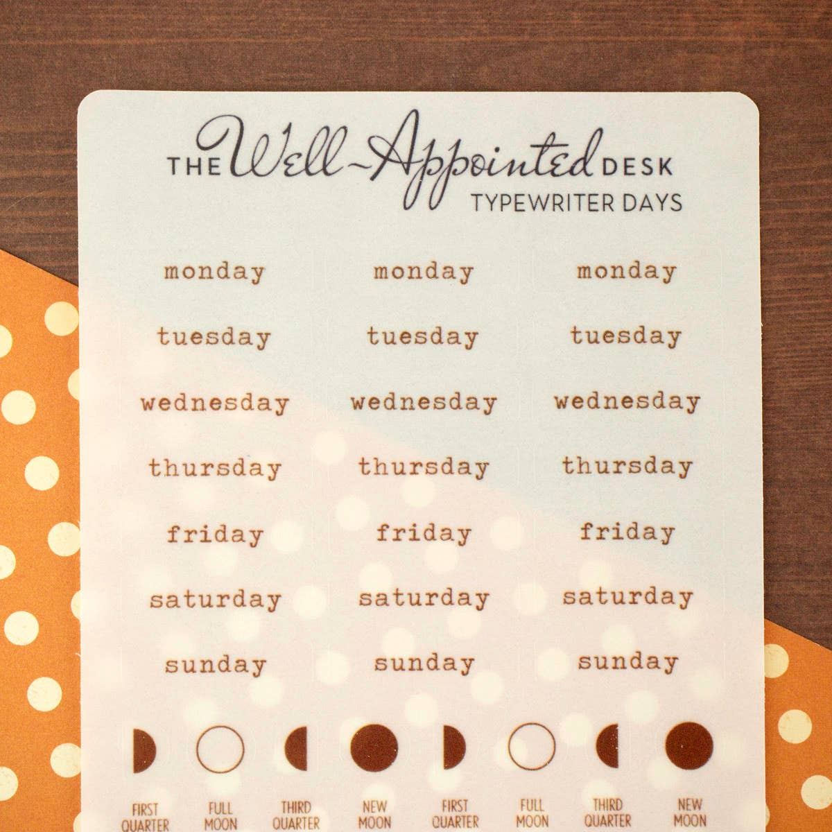 Weekly planner with days of the week and moon phases on a wooden surface.