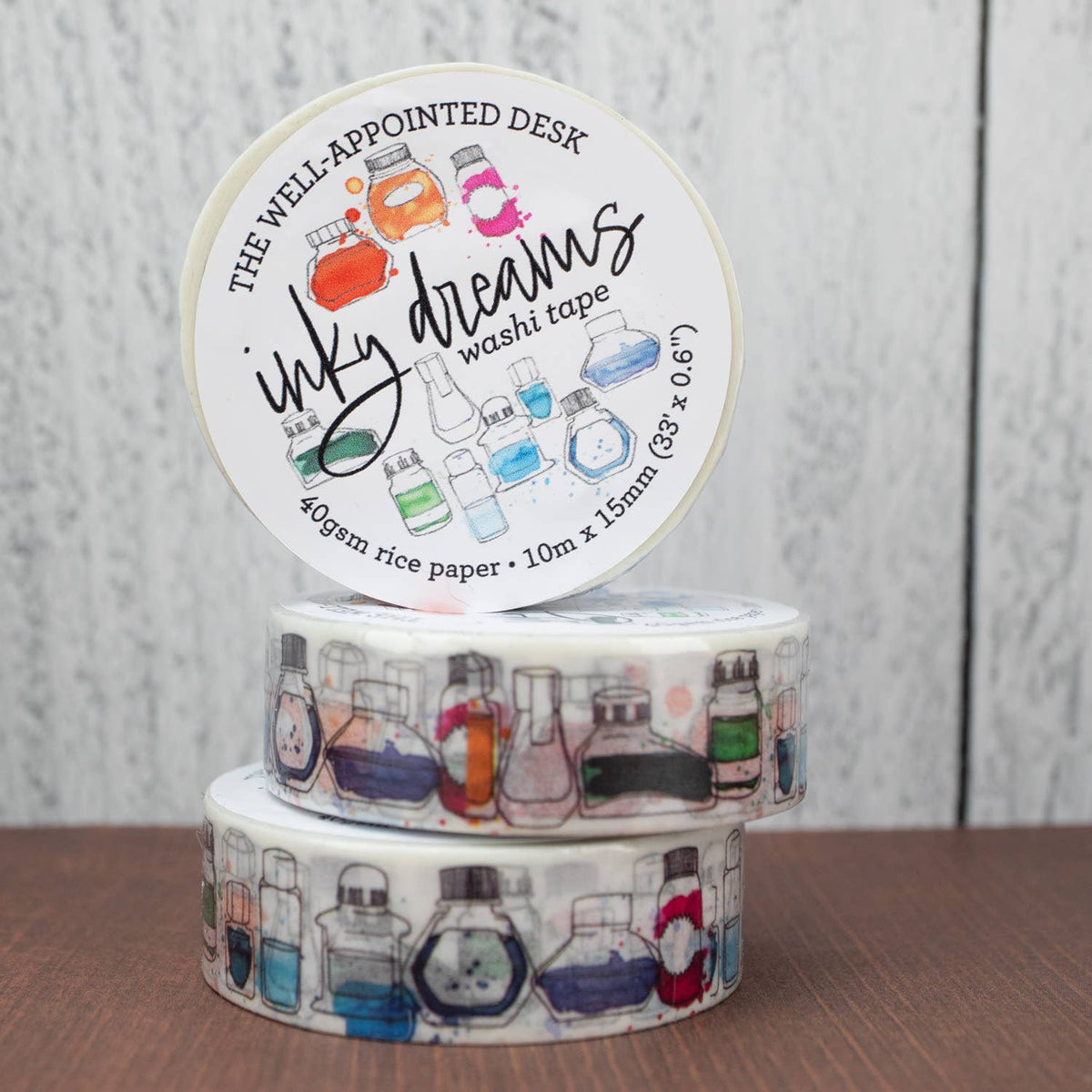 Three rolls of washi tape with decorative labels on a wooden surface.