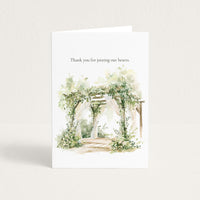 A white greeting card standing upright on a light neutral background. The card has the text 'Thank you for joining our hearts.