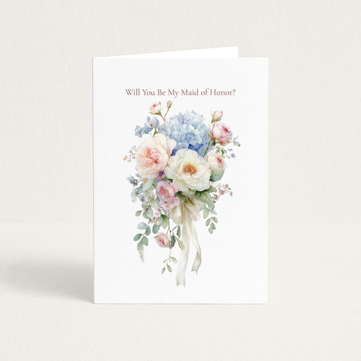 A white greeting card standing upright against a light beige background. The card features the text 'Will You Be My Maid of Honor?' above a delicate watercolor bouquet of pink, blue, and white flowers with green leaves and a white ribbon.