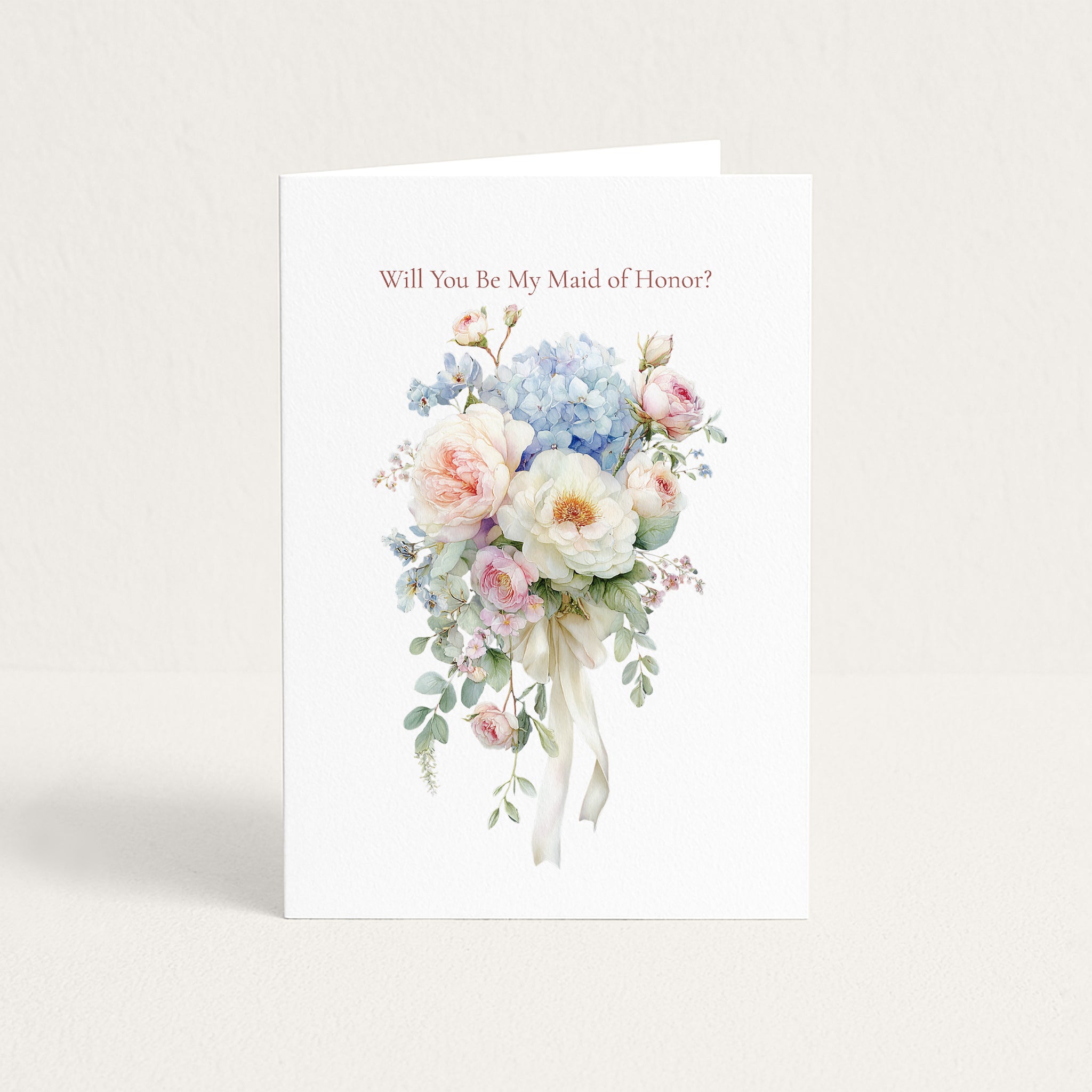 A white greeting card standing upright against a light beige background. The card features the text 'Will You Be My Maid of Honor?' above a delicate watercolor bouquet of pink, blue, and white flowers with green leaves and a white ribbon.