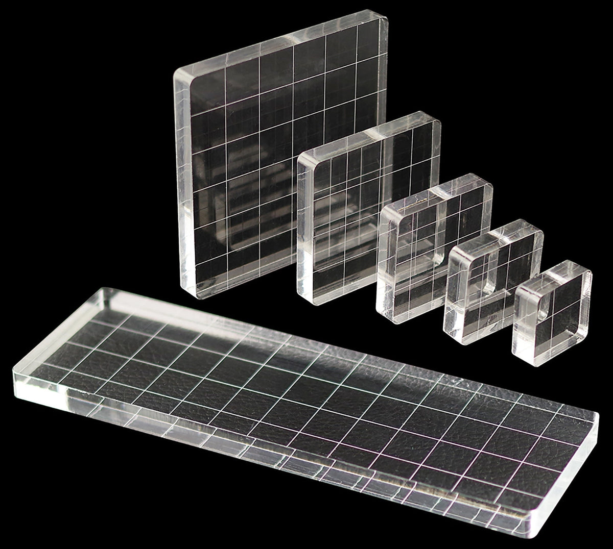 Set of clear acrylic sheets with grid patterns on a black background