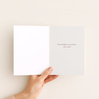 Hand holding a white card with text on a beige background