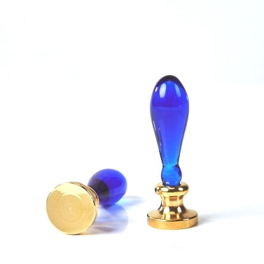 A blue glass seal stamp and its gold metal seal head, displayed on a clean white background.