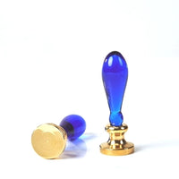 A blue glass seal stamp and its gold metal seal head, displayed on a clean white background.