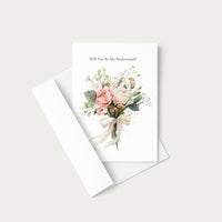 A white greeting card with the text 'Will You Be My Bridesmaid?' above a watercolor bouquet of blush pink, peach, and cream flowers with green leaves, shown with a white envelope on a light warm gray background.