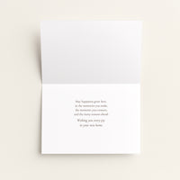 A folded white greeting card with a small centered printed message on the inside, photographed against a light warm beige background.