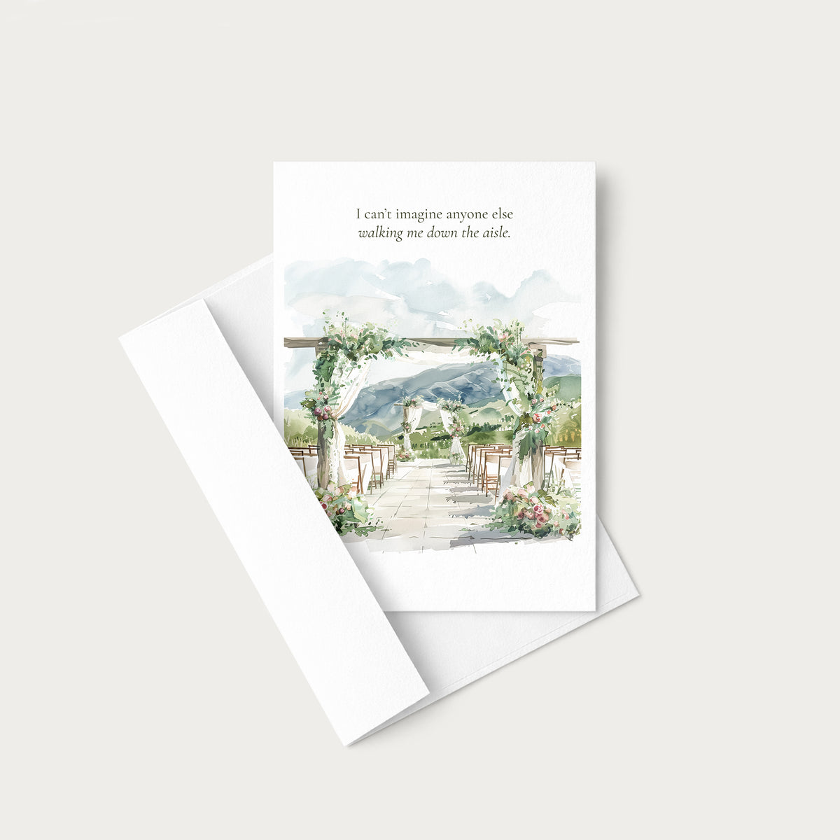 A white greeting card with a watercolor wedding aisle scene and a quote printed at the top, shown with a white envelope on a light warm gray background.