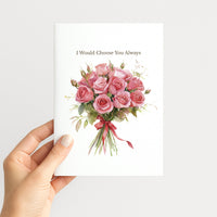 A hand holding a white greeting card with a watercolor bouquet of pink roses and the printed text 'I Would Choose You Always' on a light gray background.