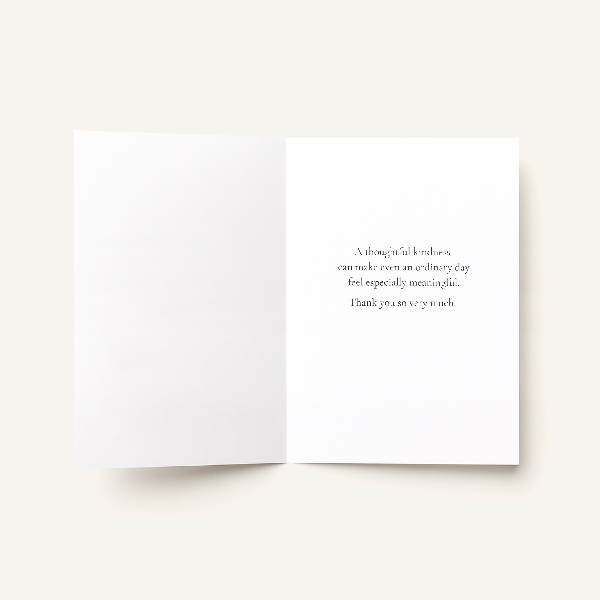 An open white greeting card on a light beige background, with a short printed message in dark gray text on the right panel.