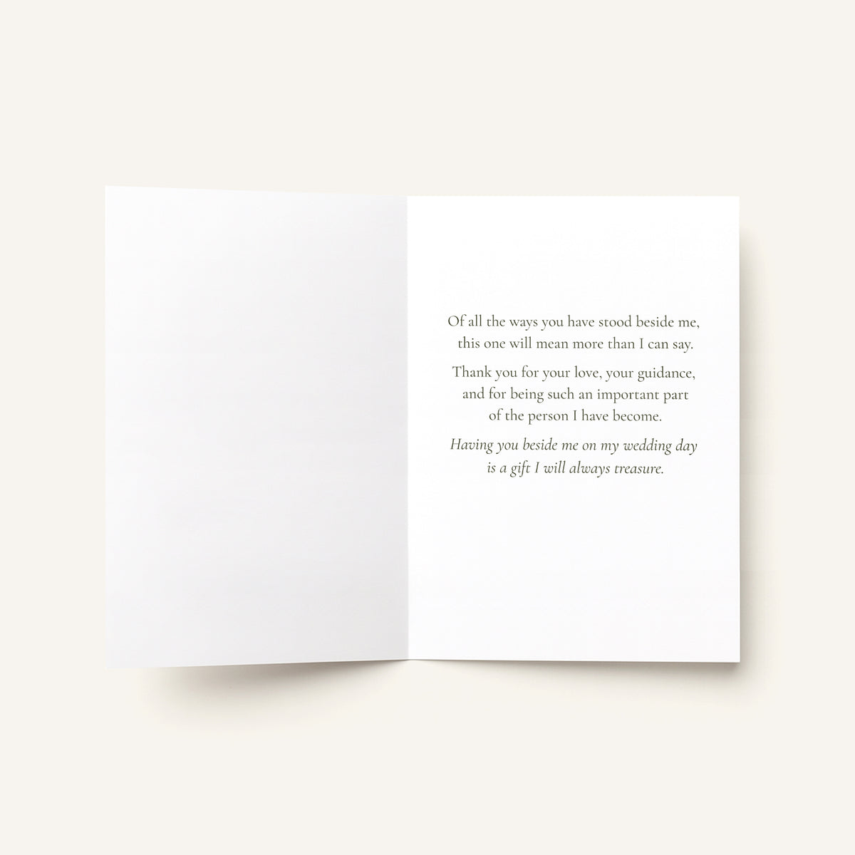An open white greeting card with elegant gray serif text printed on the right panel, photographed against a warm off-white background.