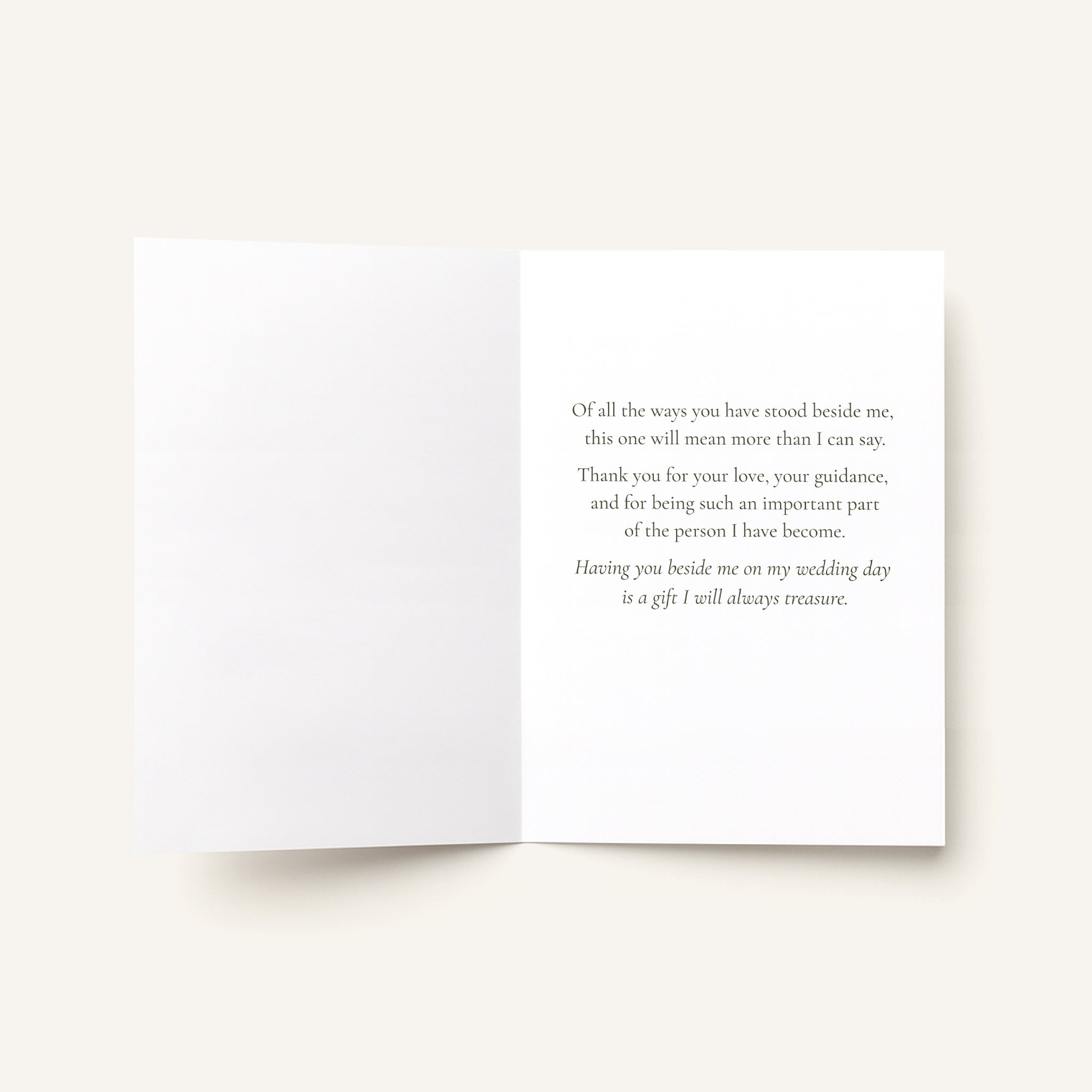 An open white greeting card with elegant gray serif text printed on the right panel, photographed against a warm off-white background.