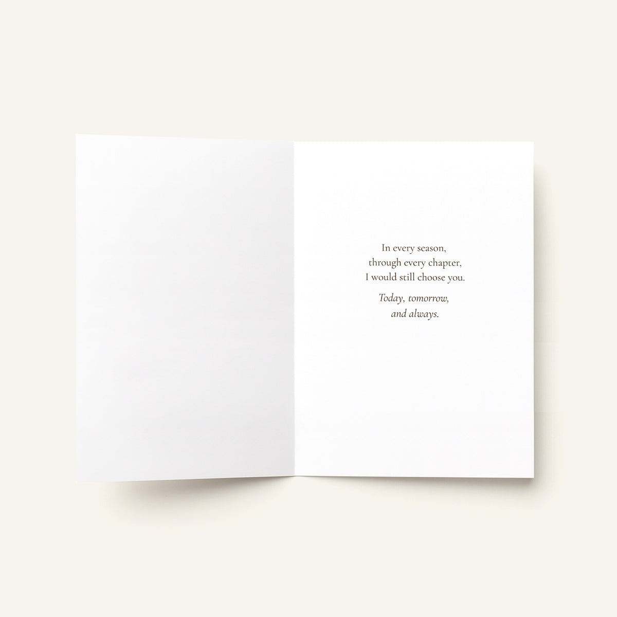 An open white greeting card or book-style insert on a light warm gray background, with a short centered quote printed in small serif text on the right page.