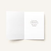 An open white greeting card or book-style insert on a light warm gray background, with a short centered quote printed in small serif text on the right page.