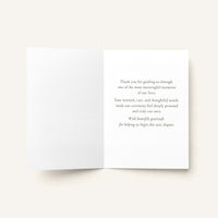 An open white greeting card with printed gray text on the right panel, photographed against a warm off-white background.