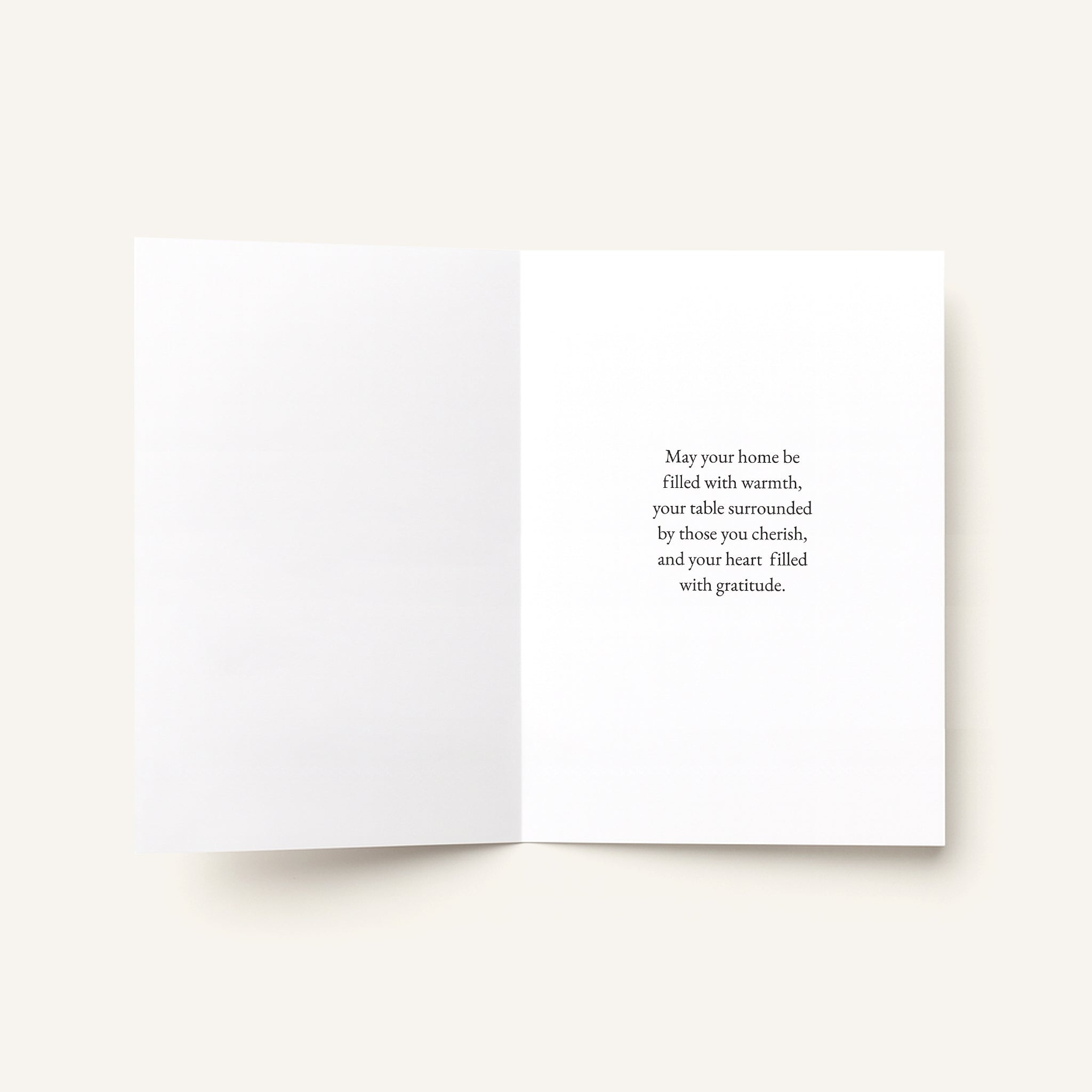An open white greeting card with a warm message printed in black serif text on the right panel, photographed on a light warm beige background.
