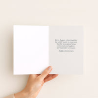 Open Celebrating Your Story anniversary card held by hand, showing a message about shared years, joy, and treasured memories.