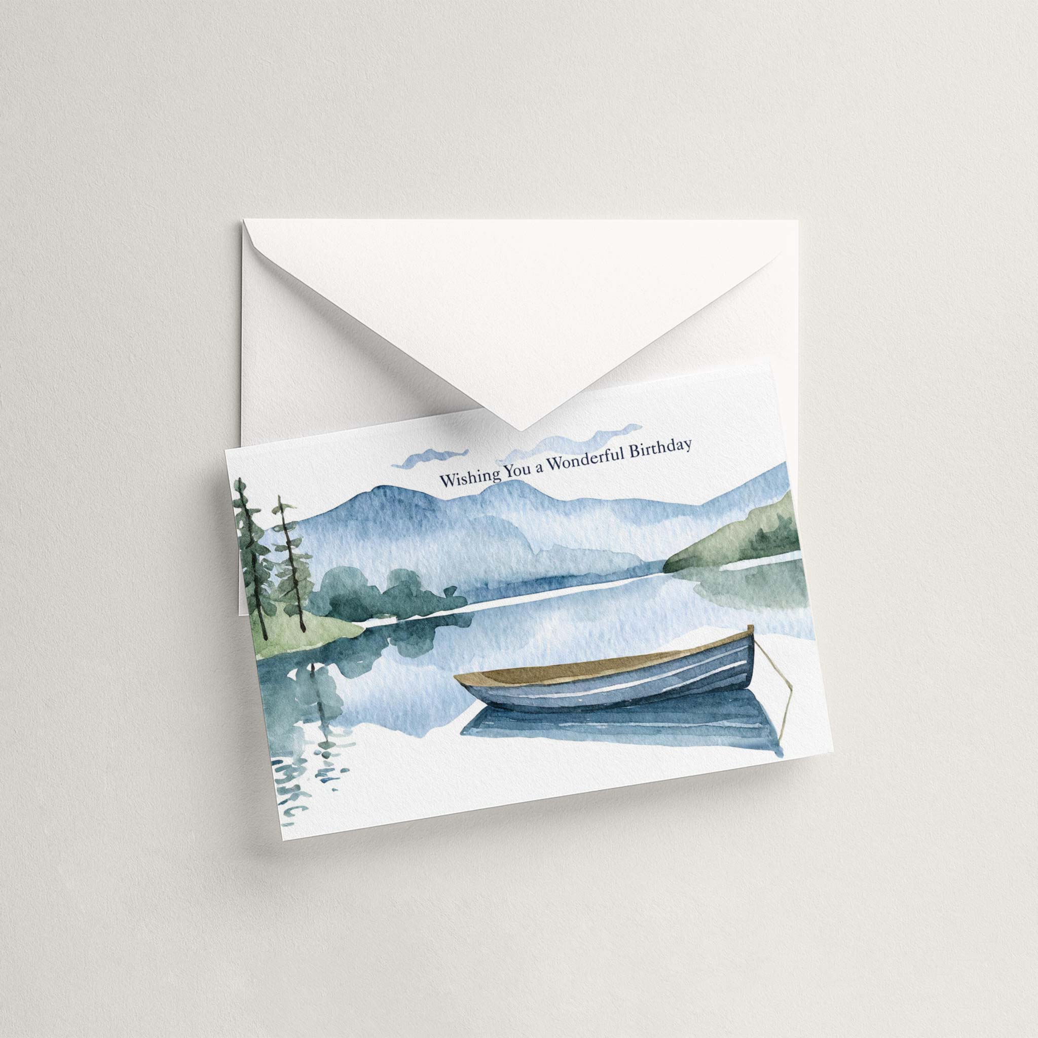 Watercolor lake and rowboat birthday card displayed with a coordinating white pointed-flap envelope.