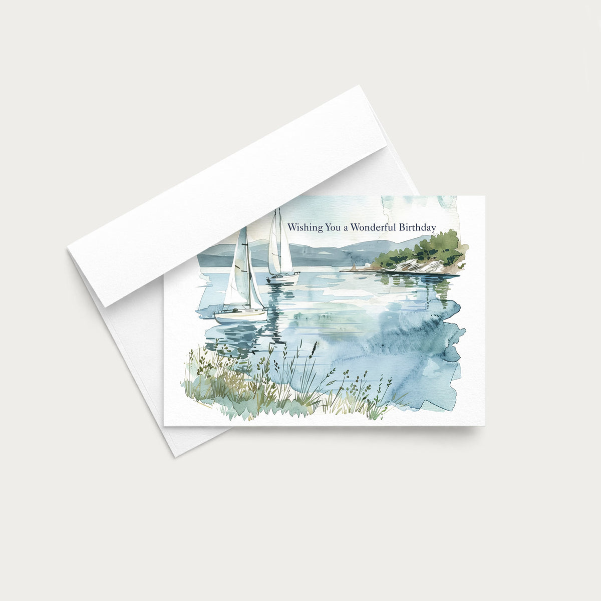 A vertical birthday greeting card with a watercolor landscape illustration in blue, green, and beige tones, shown with its white envelope on a light warm gray background. The card reads 'Wishing You a Wonderful Birthday'.