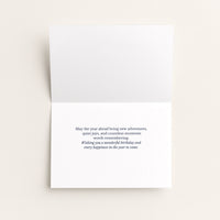Open birthday card showing the message “May the year ahead bring new adventures, quiet joys, and countless moments worth remembering.”