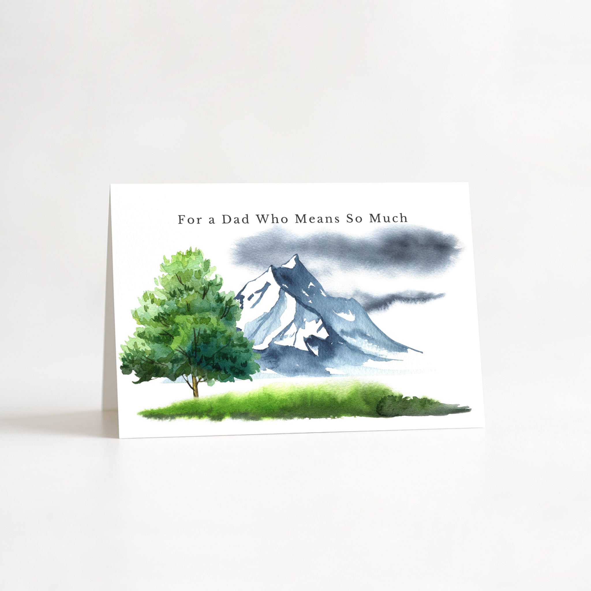 For a Dad Who Means So Much birthday card featuring a watercolor mountain, evergreen tree, and green landscape.