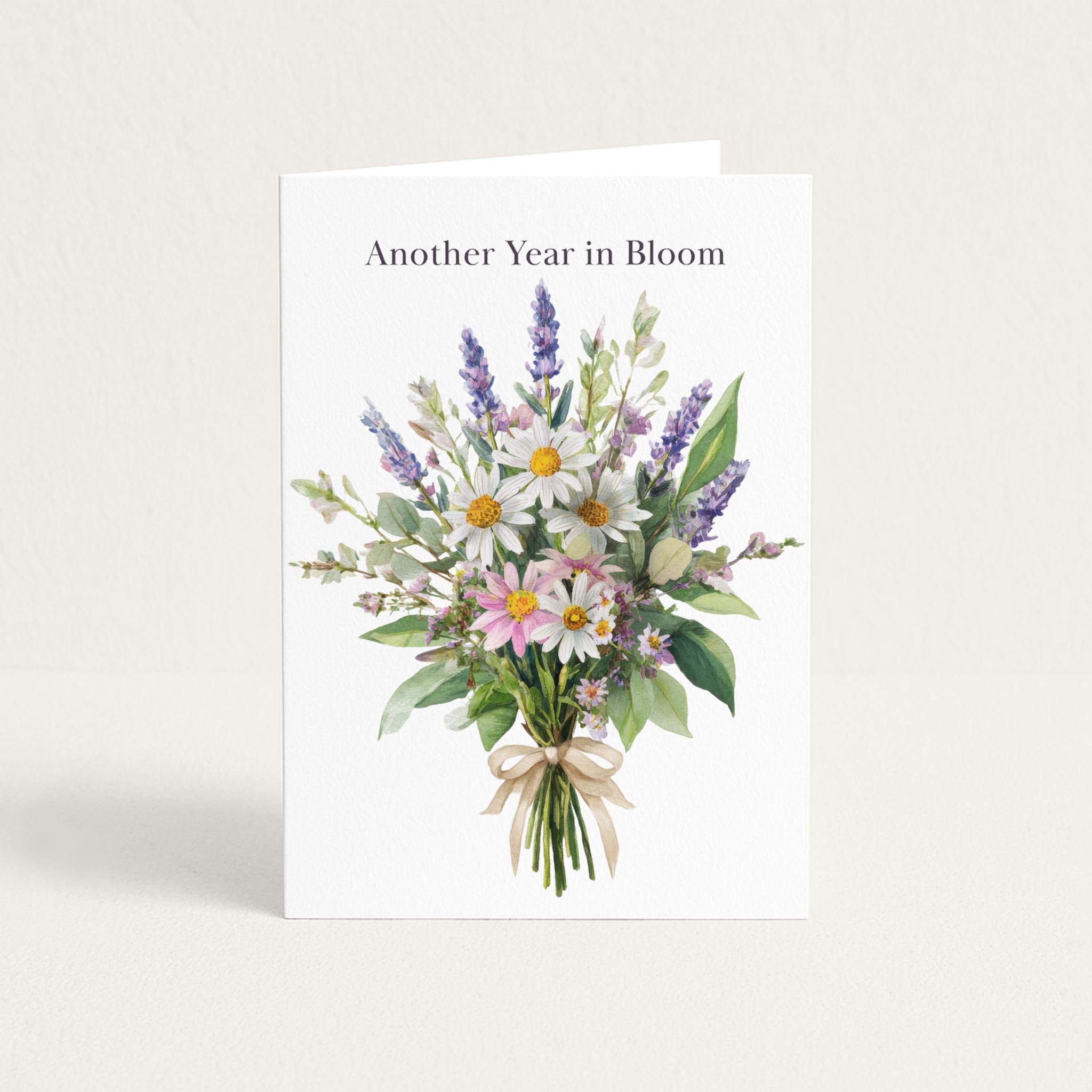 Another Year in Bloom birthday card featuring a watercolor bouquet of daisies, lavender, and soft pink flowers.