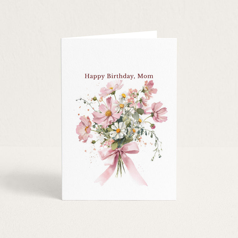 Happy Birthday, Mom card featuring a watercolor bouquet of pink cosmos and white daisies tied with a pink ribbon.