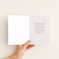 Open birthday card for a dear friend held by hand, showing a message celebrating kindness, laughter, and friendship.