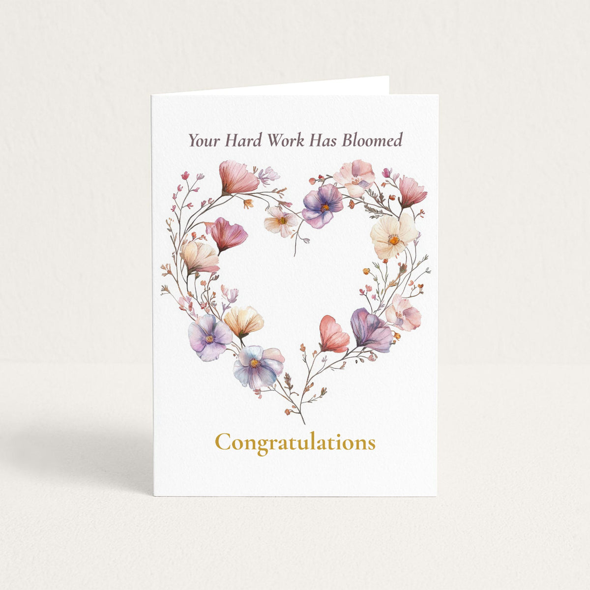 Congratulations card featuring a heart-shaped wreath of pink, lavender, and cream watercolor flowers with the message “Your Hard Work Has Bloomed.”