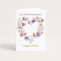 Congratulations card featuring a heart-shaped wreath of pink, lavender, and cream watercolor flowers with the message “Your Hard Work Has Bloomed.”