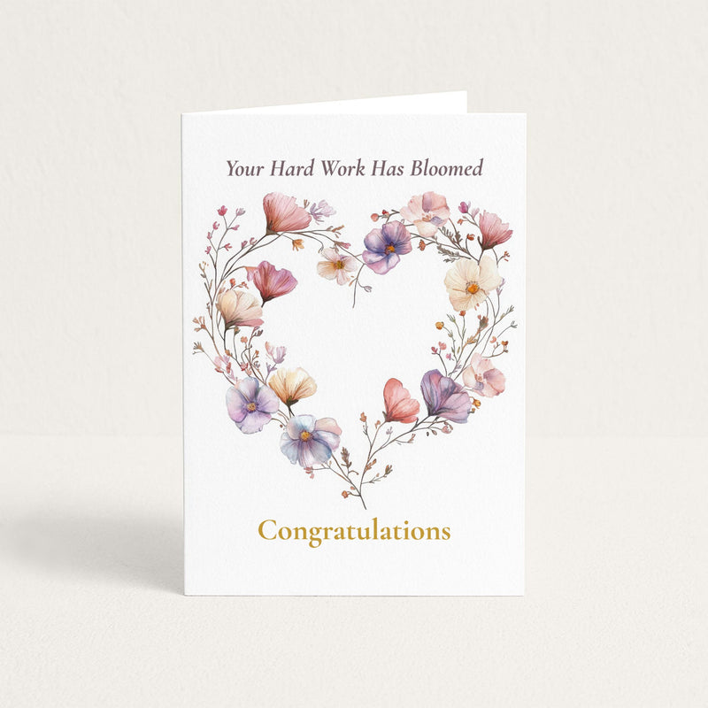 Congratulations card featuring a heart-shaped wreath of pink, lavender, and cream watercolor flowers with the message “Your Hard Work Has Bloomed.”