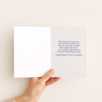 Open retirement card held in hand, showing a message about freedom, simple pleasures, and new opportunities.