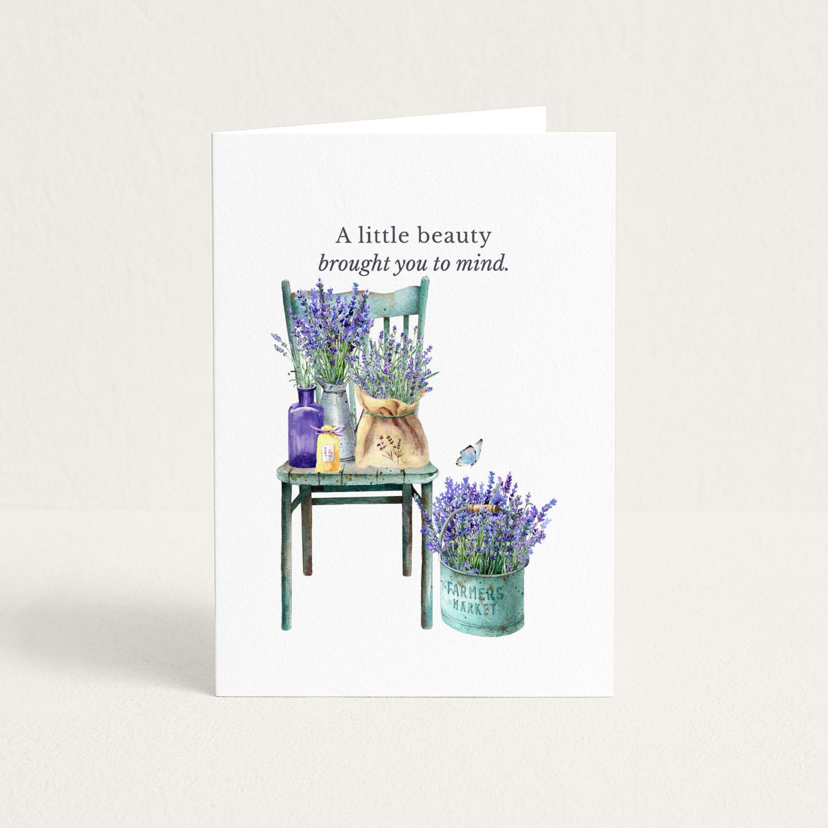Friendship card featuring watercolor lavender arranged on a vintage green chair and in a market pail, with the message “When I see the beauty of lavender in Provence, I think of you.”