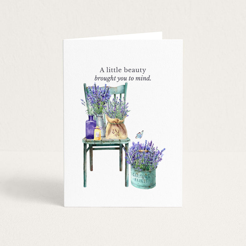 Friendship card featuring watercolor lavender arranged on a vintage green chair and in a market pail, with the message “When I see the beauty of lavender in Provence, I think of you.”
