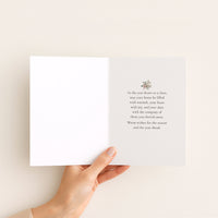 Open seasonal card held in hand, showing a small winter greenery motif and a message wishing warmth, joy, and cherished company.