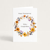 Thanksgiving greeting card featuring a delicate autumn floral wreath in orange, purple, and blue with “With a Grateful Heart.”