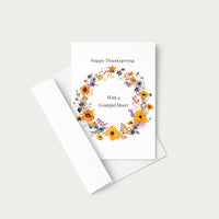 Thanksgiving floral wreath greeting card displayed with a coordinating white envelope on a neutral background.