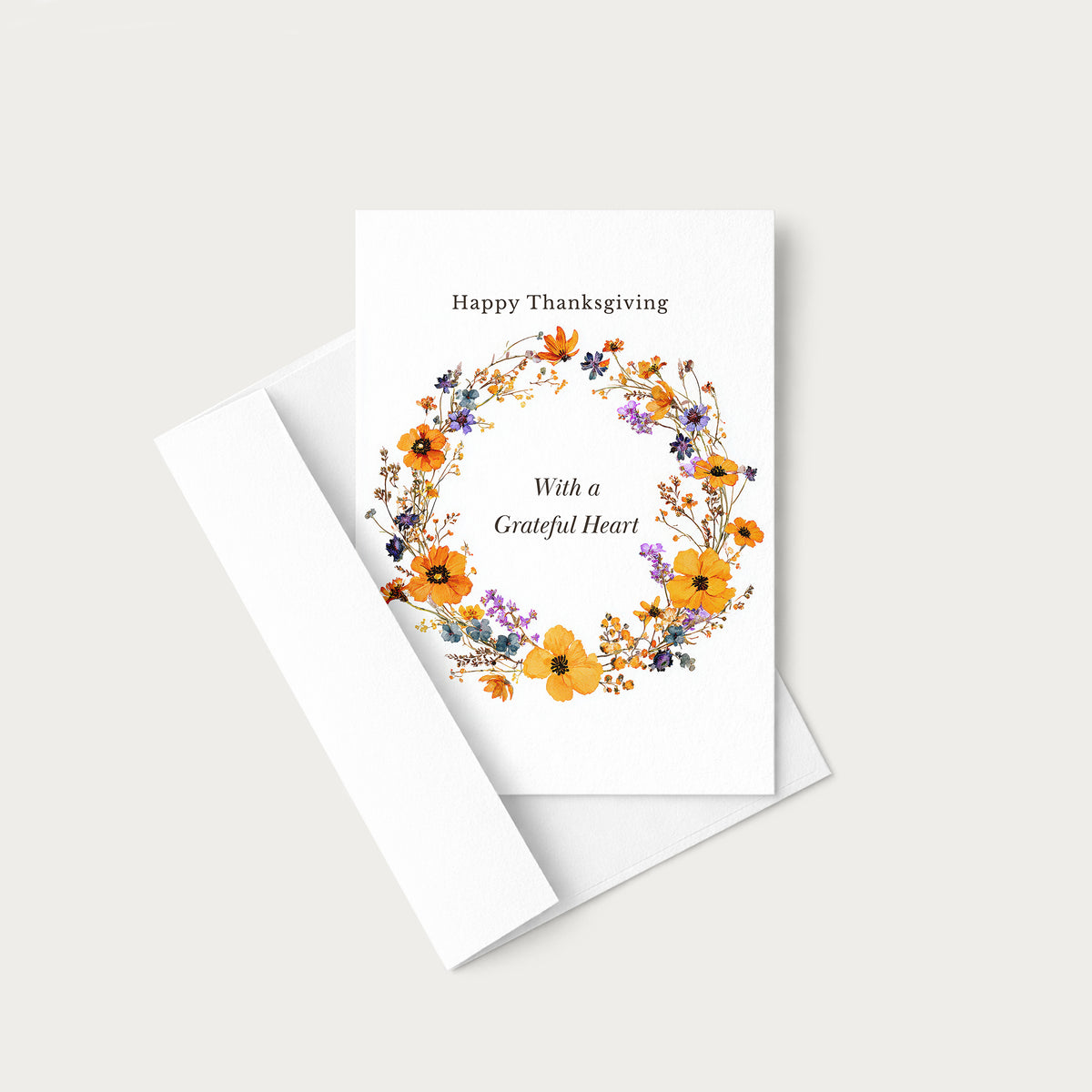 Thanksgiving floral wreath greeting card displayed with a coordinating white envelope on a neutral background.