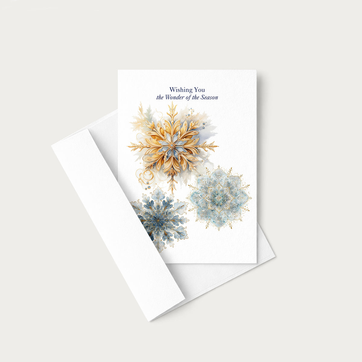 Blue and gold snowflake holiday greeting card displayed with a coordinating white envelope on a neutral background.