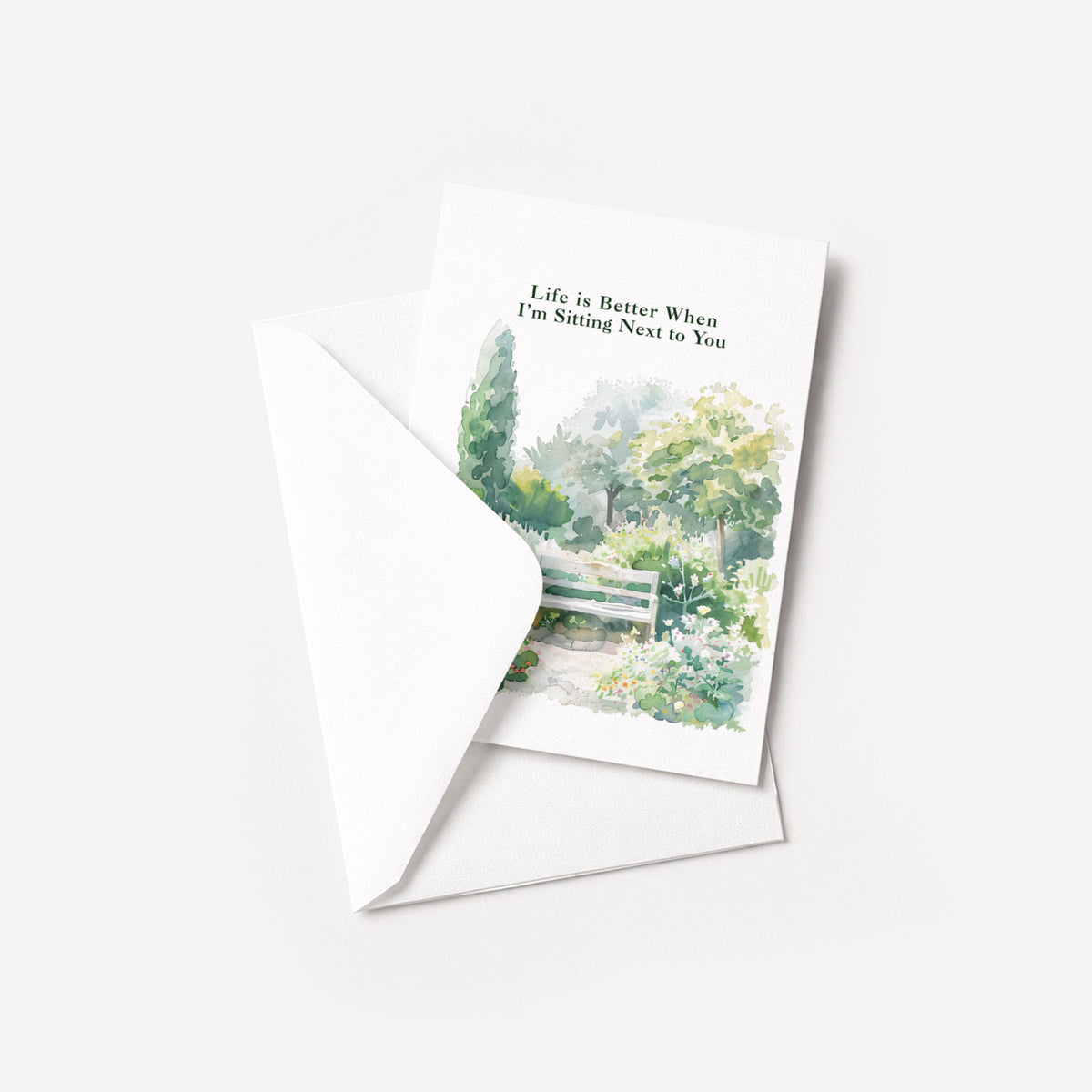 Watercolor garden bench greeting card displayed with a coordinating white envelope on a neutral background.