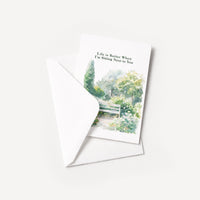 Watercolor garden bench greeting card displayed with a coordinating white envelope on a neutral background.