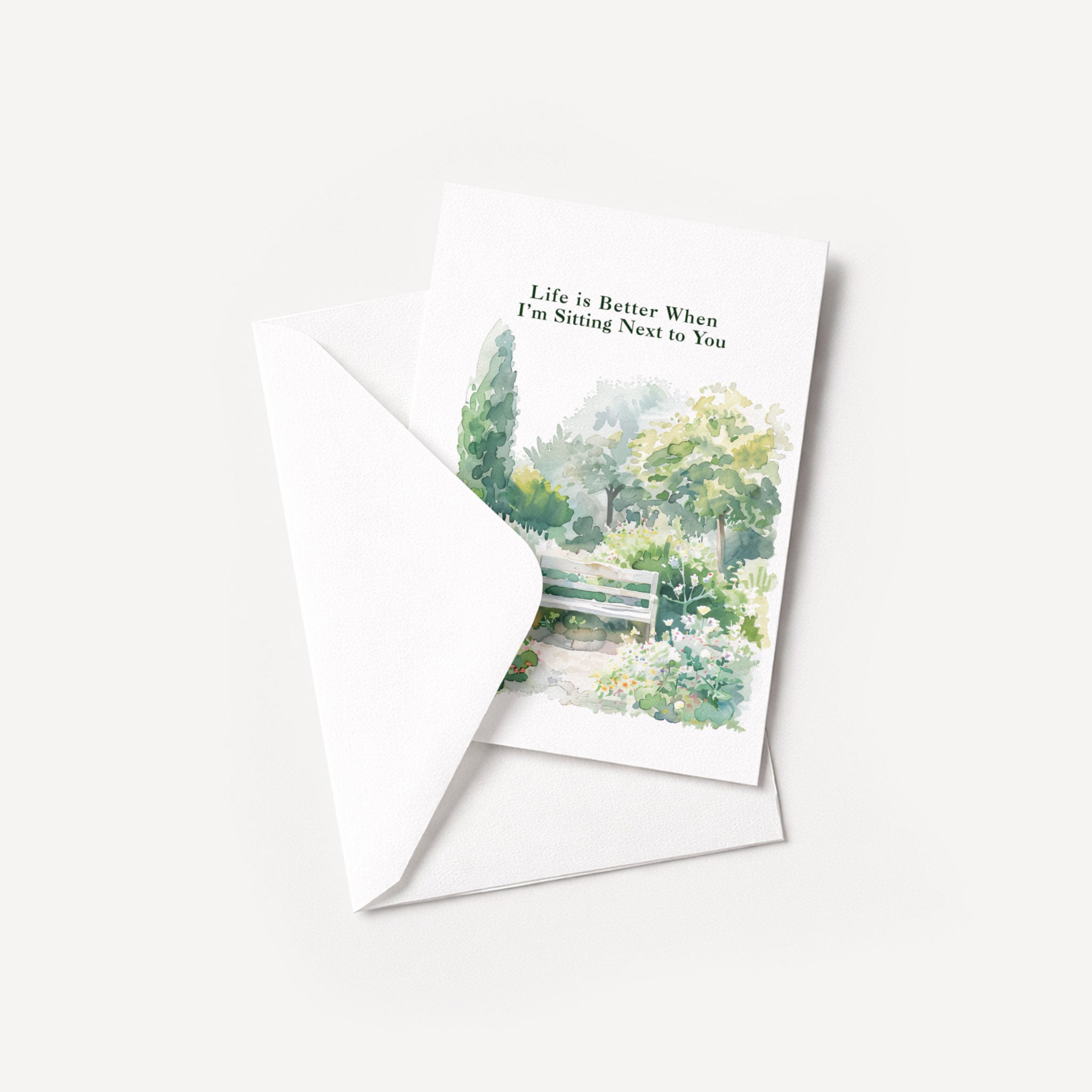 Watercolor garden bench greeting card displayed with a coordinating white envelope on a neutral background.