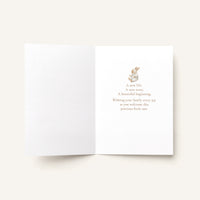 Open new baby greeting card showing the message “A new life. A new story. A beautiful beginning. Wishing your family every joy as you welcome this precious little one.”