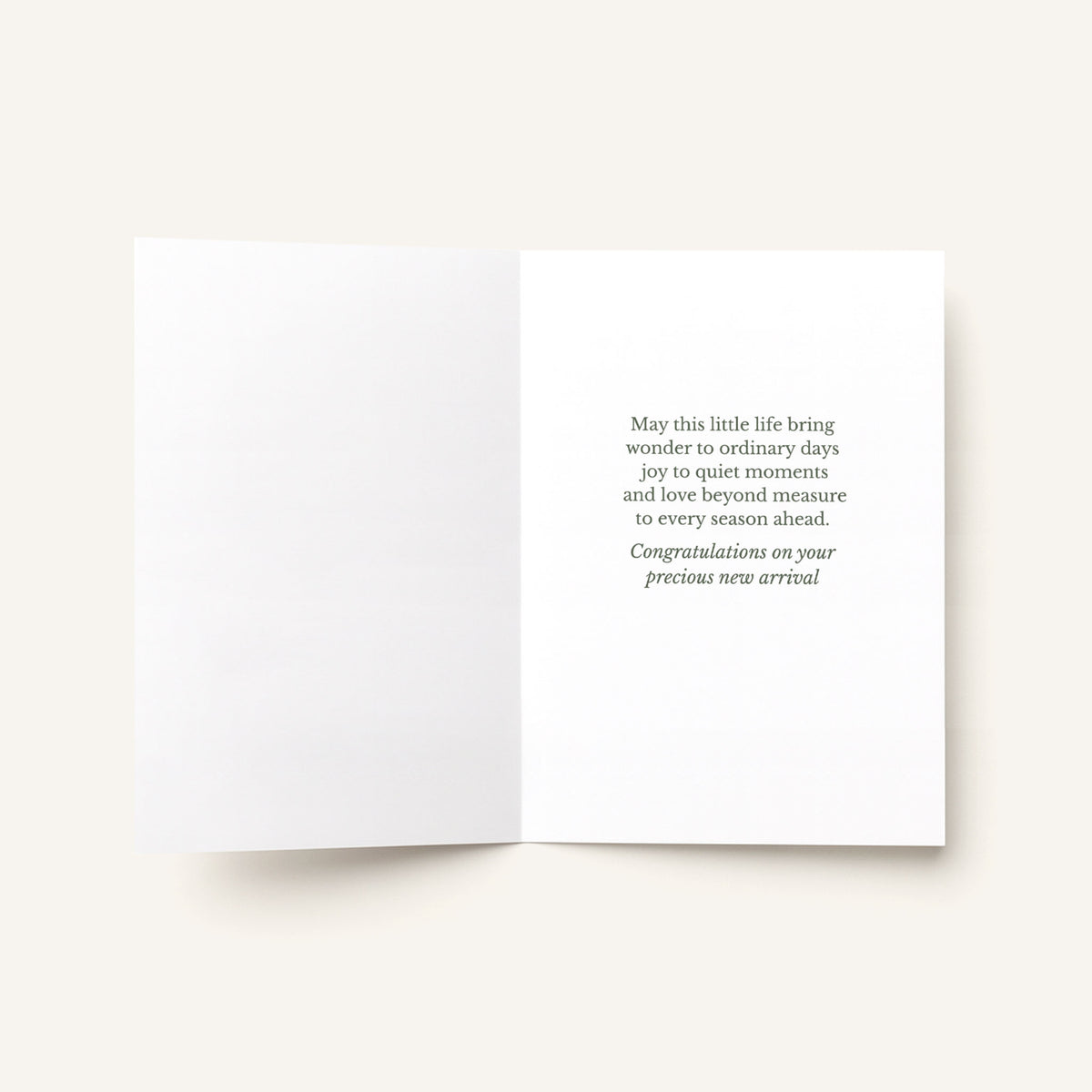 Open new baby greeting card showing the message “May this little life bring wonder to ordinary days, joy to quiet moments, and love beyond measure.”