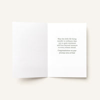 Open new baby greeting card showing the message “May this little life bring wonder to ordinary days, joy to quiet moments, and love beyond measure.”