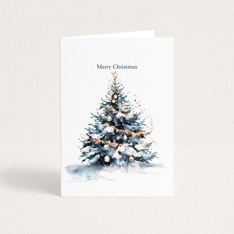 Christmas greeting card featuring a watercolor evergreen tree decorated with gold garland, ornaments, snow, and a star beneath “Merry Christmas.”