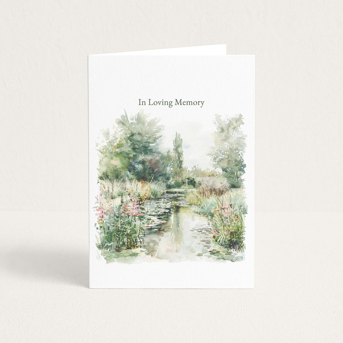 Sympathy card featuring a soft watercolor garden pond with flowers and trees beneath the words “In Loving Memory.”