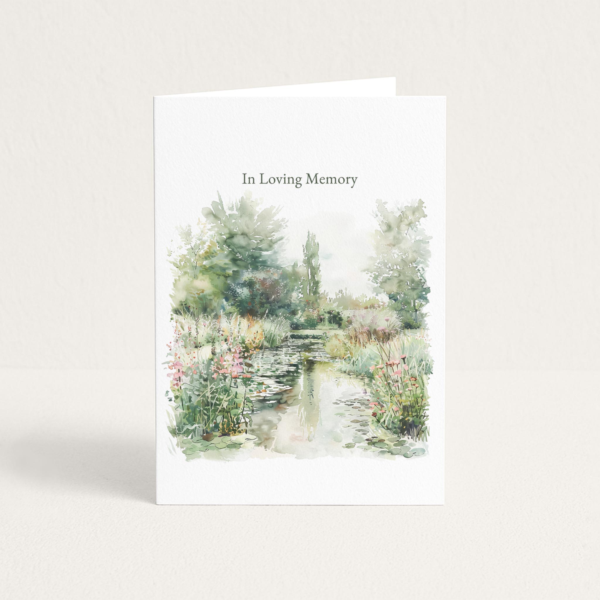 Sympathy card featuring a soft watercolor garden pond with flowers and trees beneath the words “In Loving Memory.”